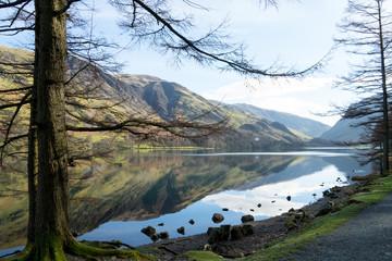 Fototapeta na wymiar Buttermere lake beautiful cold spring day with mountains and clear reflection on the water