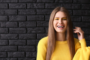 Beautiful young woman with bright makeup on dark background