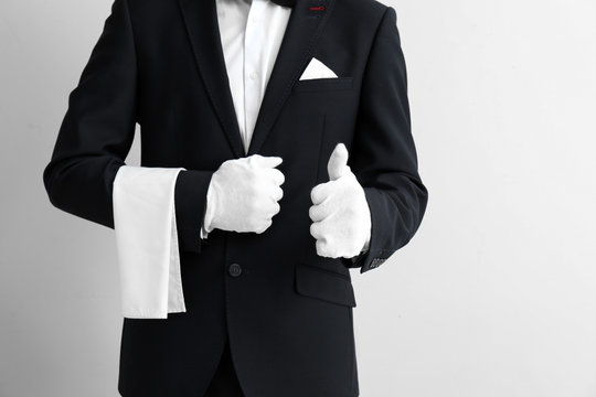 Waiter showing thumb-up on light background