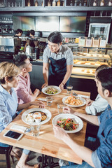 Young waiter serving food in the restaurant