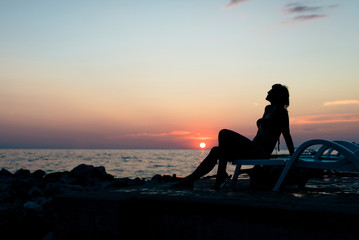 Fototapeta na wymiar A woman athletic physique spends time on the seafront and enjoying the sunset