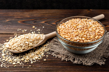 Dried pea and flakes on dark wooden background.