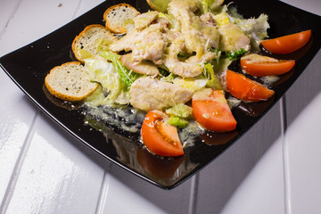 Caesar salad with bacon and quail eggs Black plate