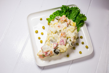 Salad with peas, mayonnaise, potatoes, sausage, cabbage, carrots and eggs