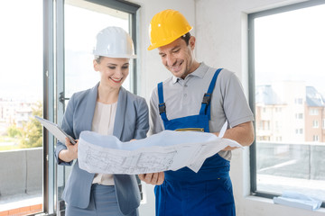 Construction worker and architect looking at plan on site
