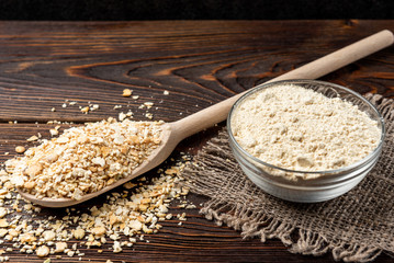 Dried pea flakes and flour on dark wooden background.