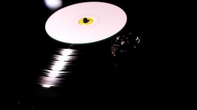 The vinyl record rotates on the player, the needle slowly descends and slides along the sound track.