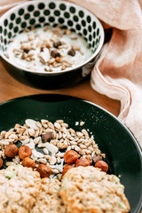 Breakfast with granola and yogurt with nuts and seeds on wood with fabric
