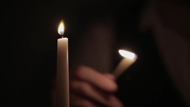 a person lights a candle with a match