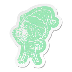 cartoon distressed sticker of a grumpy boy wearing santa hat