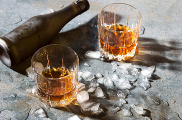 Glasses with brandy and melt ice cubes,bottle on bar counter
