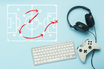 Keyboard, headphones and gamepad on a blue background. Added drawing with the tactics of the game. Football. The concept of computer games, entertainment, gaming, leisure. Flat lay, top view