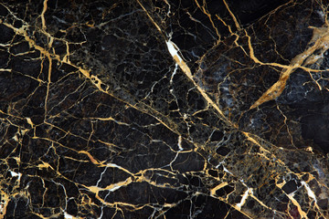 Fototapeta na wymiar The surface of the slab of dark expensive marble with yellow and white veins is called New Portoro