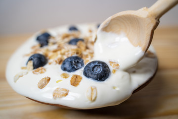 Bowl of homemade granola with yogurt and fresh berries on wooden background