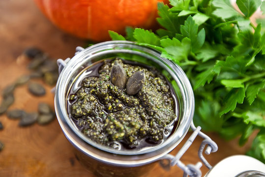 Home made pumpkin seeds pesto sauce with walnuts, olive oil, salt, greens and spices in a jar, vegan, vegetarian healthy food concept.