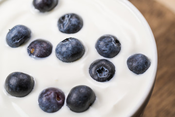 Bowl of homemade granola with yogurt and fresh berries on wooden background