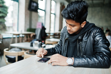 Asian male casual man holding smartphone, tapping on screen while sitting on cafe.