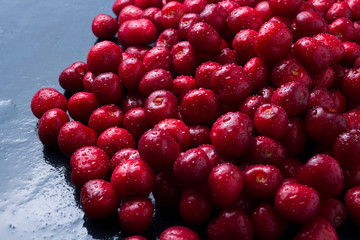 Freshly picked cherries with drops of dew and water on a dark blue stone background. The concept of harvesting. Flat lay, top view