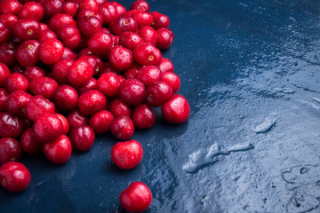 Freshly picked cherries with drops of dew and water on a dark blue stone background. The concept of harvesting. Flat lay, top view
