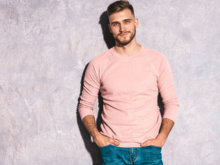 Portrait of handsome smiling hipster lumbersexual businessman model wearing casual summer pink clothes. Fashion stylish man posing against gray wall