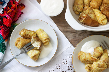 Homemade pancakes stuffed with cottage cheese with raisins, served with sour cream and cherry.