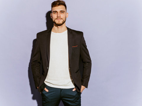 Portrait of handsome serious hipster lumbersexual businessman model wearing casual black suit. Fashion stylish man posing in studio