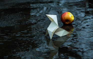 Origami paper figure on the background of a gloomy city street and puddles