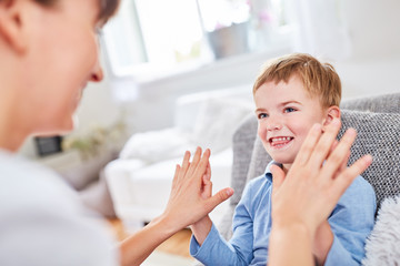 Fröhlicher Junge berührt Hände der Mutter