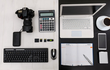 Workplace with laptop and digital camera top view