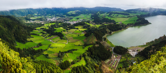 Fototapeta na wymiar Panoramic landscape with aerial view on beautiful blue green crater lake Lagoa das Furnas and village Furnas with vulcanic thermal area. Sao Miguel, Azores, Portugal. Countryside landscape with green
