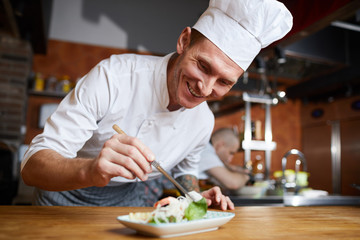 Fototapeta na wymiar Portrait of professional chef plating Asian seafood dish in restaurant, copy space