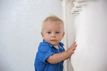 Naklejka premium Sweet toddler boy in garden, eating freshly baked scones with cream and jam