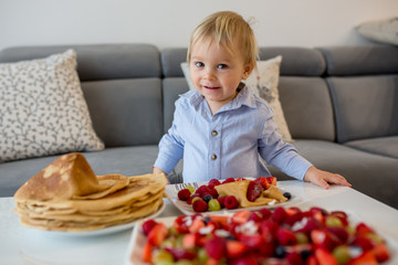 Toddler child, boy, eating pancakes with lots of fruits and juice