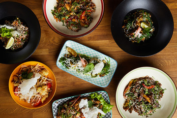 Top view closeup of several Asian food dishes on wooden background, copy space