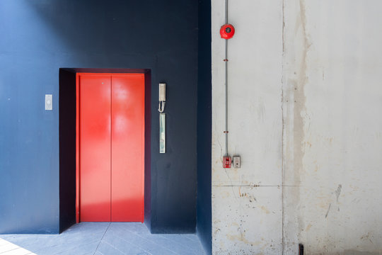 red elevator and black wall with fire alarm, telephone.