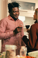 Smiling man looking at his girlfriend while drinking wine with her