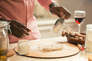 Man sifting flour on the dough while cooking