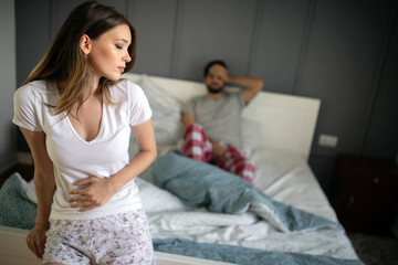 Sad, upset, unhappy woman holding hands on stomach suffering from stomach pain