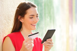 Happy woman pays online with credit card and smart phone