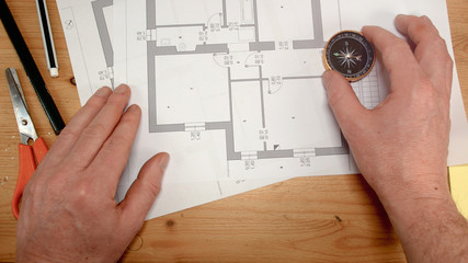 top view, an architect's hand with a compass looks for the orientation of the north pole, ideal footage for topics such as building renovation, design, new home and family