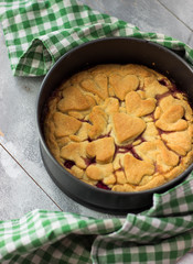 Cherry pie in baking tin on a wooden table. Fresh Homemade bakery products