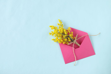 ショッキングピンクの封筒に入ったミモザの花束