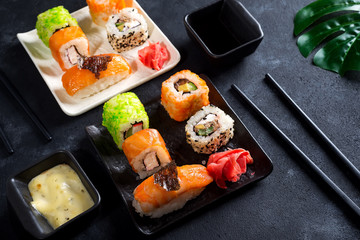 Traditional Japanese food- sushi, rolls, chopsticks, soy sauce on black slate background. Sushi menu. Top view copy space