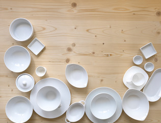 modern, white crockery, in different designs, stands on a light wooden background