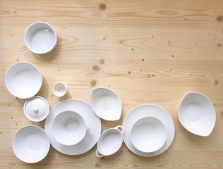 modern, white crockery, in different designs, stands on a light wooden background