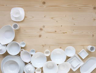 modern, white crockery, in different designs, stands on a light wooden background