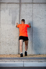 Fototapeta na wymiar Man warming up for running. Earphones in ears, sportswear on. Healthy lifestyle concept.