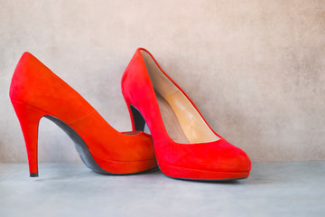 Bright orange high-heeled shoes on gray background.