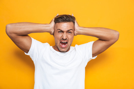 Image of angry guy 30s in white t-shirt screaming and grabbing head
