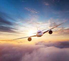 Fototapeta premium Commercial airplane flying over dramatic sunset
